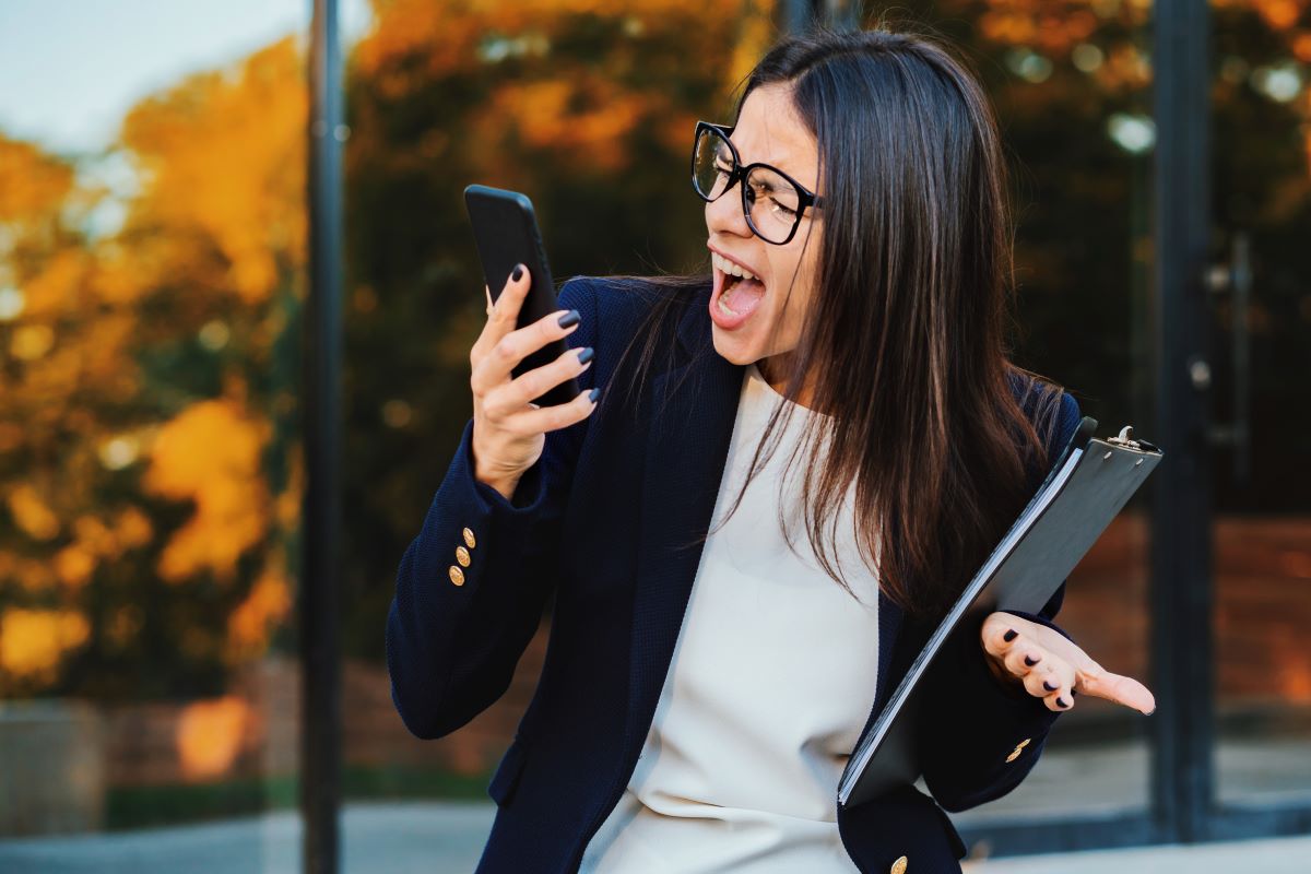 Como superar experiências ruins - Empresária gritando no celular Tendo um colapso nervoso no trabalho, gritando de raiva