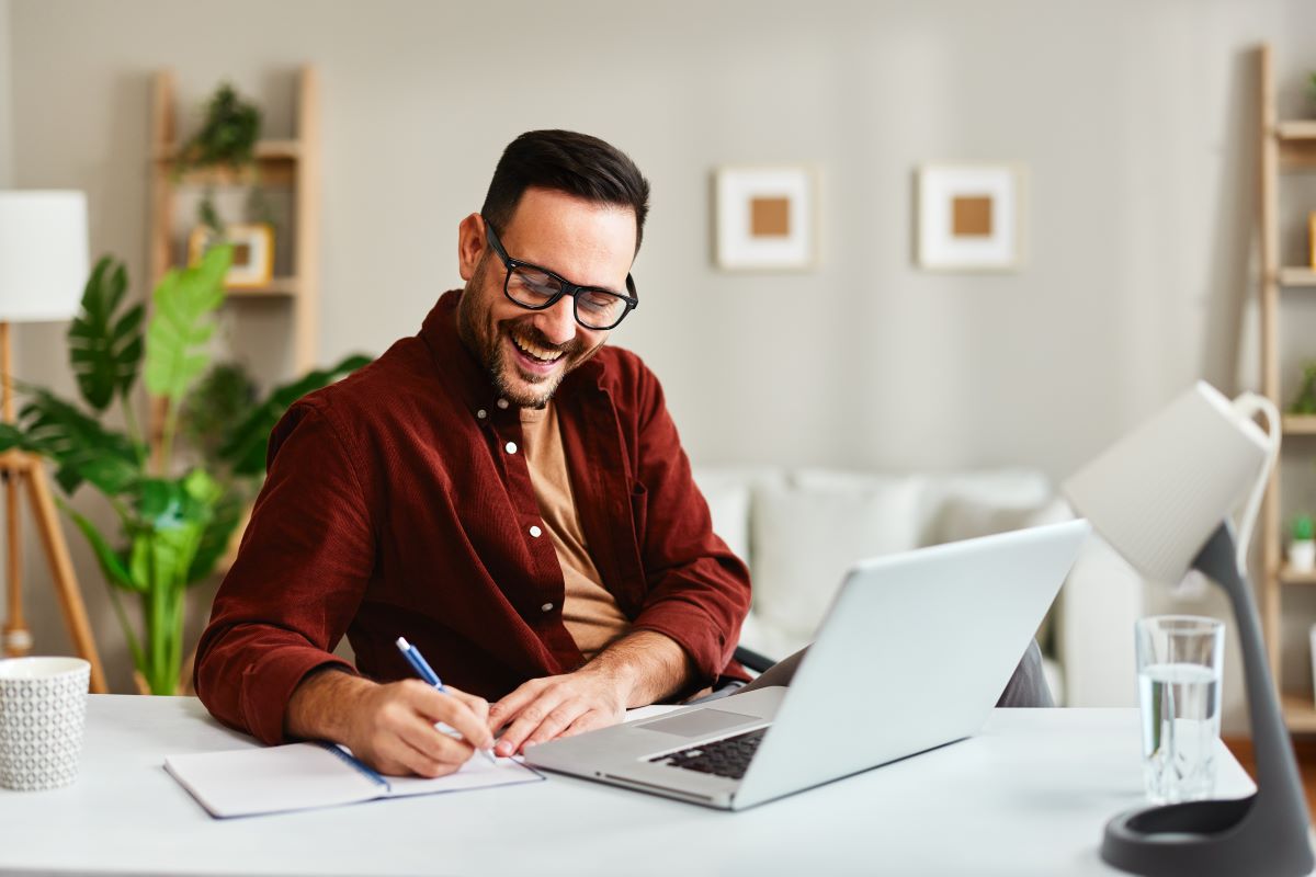 Conteúdo Valioso - Jovem empresário trabalhando em casa com laptop e papéis na mesa